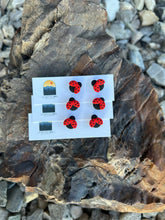 Load image into Gallery viewer, Three pairs of red and black ladybug clay studs on display cards against tree bark.