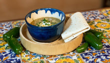 Load image into Gallery viewer, Bowl of LuLu’s Homestyle Green Chili topped with melted cheese, sour cream, and cilantro, served with a warm tortilla.