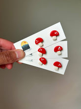 Load image into Gallery viewer, Three pairs of red mushroom clay studs with white spots on display cards.
